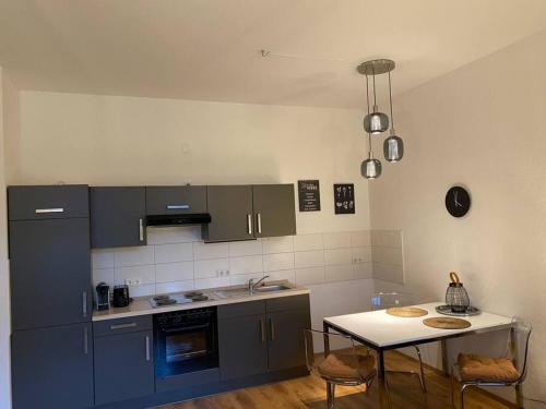 een keuken met blauwe kasten en een tafel met stoelen bij Exkl. helles Apartment mit Balkon, WLAN& Parkplatz in Maagdenburg