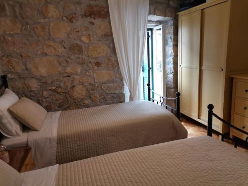 a bedroom with two beds and a stone wall at House Marineta - Makarska promenade in Makarska
