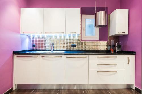 a kitchen with white cabinets and purple walls at Merveilleux 2P, à 50 m de la plage, en plein centre ville in Menton