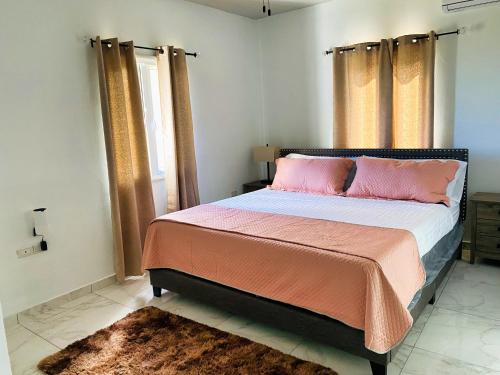 1 dormitorio con 1 cama grande con almohadas rosas en Sea-Renity en Oyster Pond