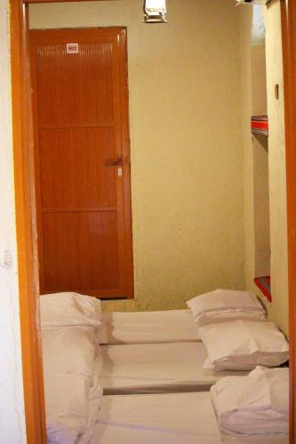 three beds in a room with a wooden door at Mahalli Balad Sayt Heritage Inn in Bilād Sayt