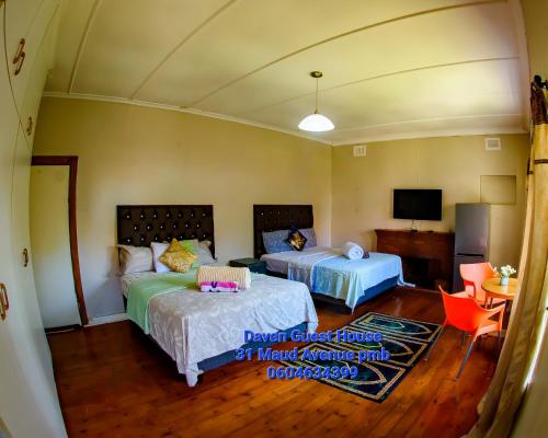 a bedroom with two beds and a table and a tv at Daven Guest House (DGH) in Pietermaritzburg