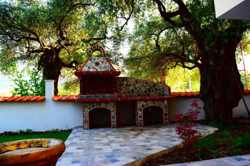 a house with a brick fireplace next to a tree at Tsafas Αpartments in Limenas