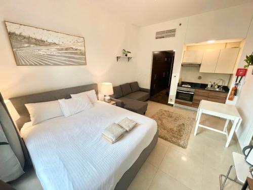 ein Schlafzimmer mit einem großen weißen Bett und ein Wohnzimmer in der Unterkunft Super Elegant studio apartment-Sparkle tower By SWEET HOMES in Dubai