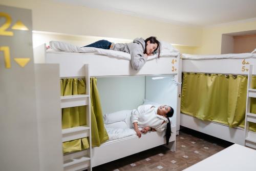 two men laying on bunk beds in a hostel at Уютный Sunny hostel in Almaty