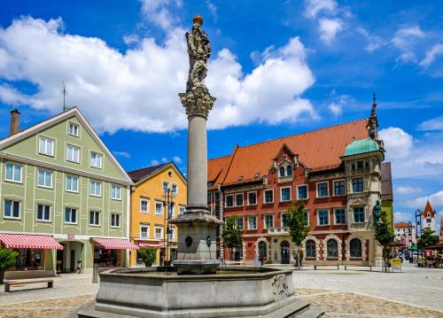a statue in the middle of a town with buildings at MOREHOME-Apartments in Mindelheim