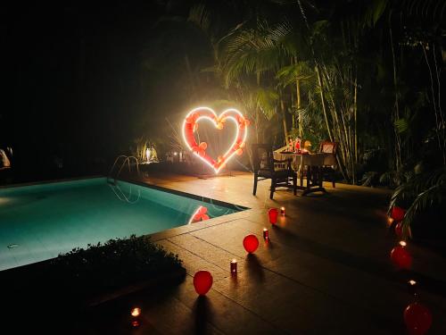 a heart lights up a swimming pool at night at Greenwoods Resort, Thekkady in Thekkady