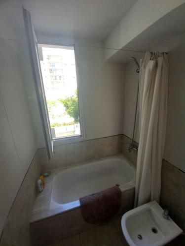 baño con bañera, lavabo y ventana en Playa 2 en Mar del Plata