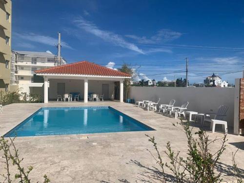 a swimming pool with chairs and a house at Iris Vacation Lovely Place in La Romana