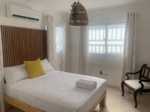 a bedroom with a white bed and a chair at Iris Vacation Lovely Place in La Romana