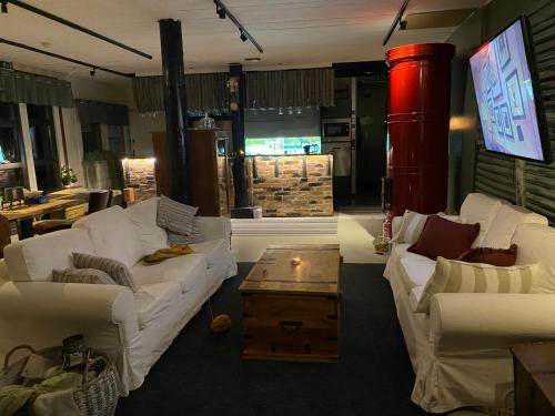ein Wohnzimmer mit weißen Sofas und einem TV in der Unterkunft Vanha Ravintola Ölvin Suolatorilla - Vanhan Kanttorilan yhteydessä in Lovisa