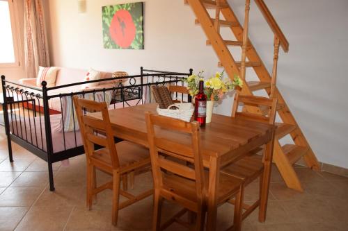a dining room with a wooden table and a staircase at Rastoni Apartments in Andros