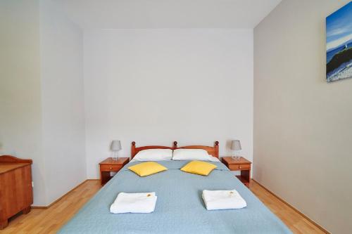 a bedroom with a blue bed with two yellow pillows at Hotelik Gołdap in Gołdap