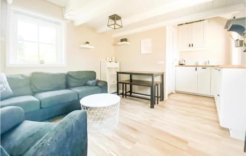 a living room with a blue couch and a kitchen at 1 Bedroom Gorgeous Home In Zoutelande in Zoutelande