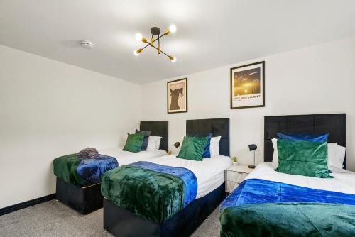 2 letti in una camera con verde e bianco di Elegant Yorkshire Abode - Great Location - Sleeps 19 a Castleford