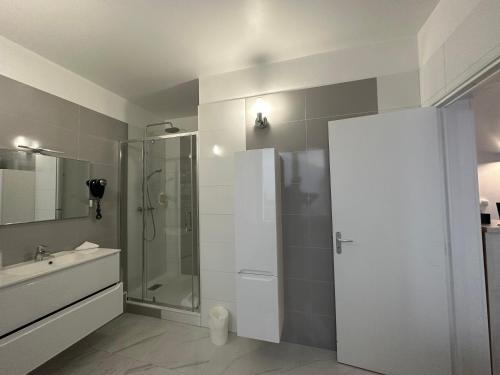 a white bathroom with a shower and a sink at Hotel Le Saint-Yves in Le Tréport
