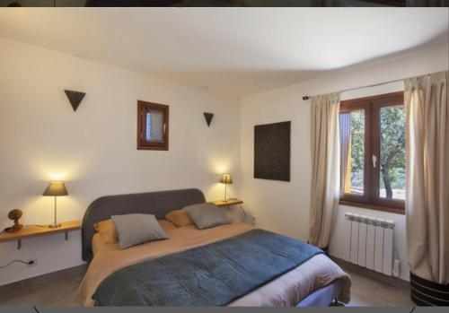 ein Schlafzimmer mit einem großen Bett und einem Fenster in der Unterkunft Le MONTE-CINTO -LOCATION EN PIERRE ENTRE MER ET MONTAGNE in Moltifao