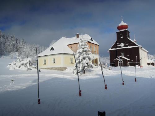 una iglesia en la nieve al lado de un edificio en Chalupa Fara, en Dolní Malá Úpa