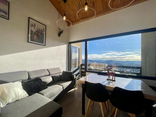 - un salon avec un canapé, une table et une grande fenêtre dans l'établissement Le Sirac, T3 au pied des pistes de Chaillol, à Saint-Michel-de-Chaillol