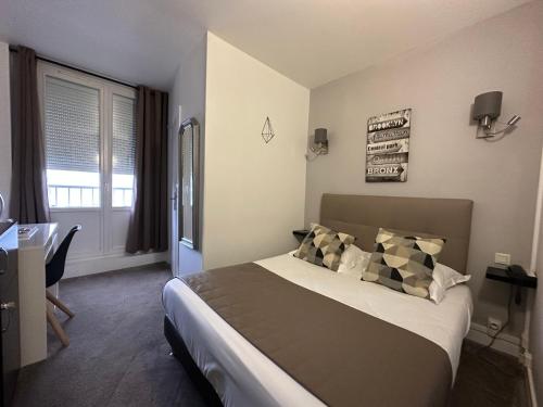 a bedroom with a bed and a desk and a window at Hotel Le Saint-Yves in Le Tréport