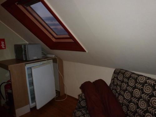 a room with a couch and a window in a attic at Guesthouse Kolibriehuys in Nieuwkerke