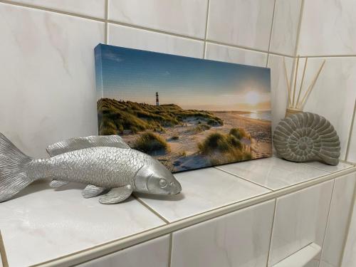 a fish on a shelf next to a picture of a beach at Ferienwohnung Landidylle in Gieckau
