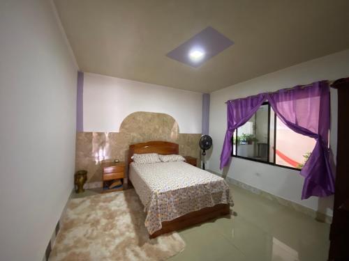 1 dormitorio con 1 cama y una ventana con cortinas moradas en Casa en san Cristobal, en Puerto Baquerizo Moreno