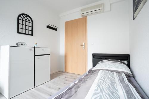 a small bedroom with a bed and a refrigerator at CaSa Apartment Svea - 2x Parken-Amazon Prime-Terasse-Garten-Vollausstattung in Erfurt