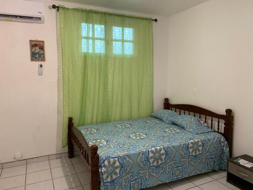 a bedroom with a bed and a green window at Chez Marc in Les Abymes