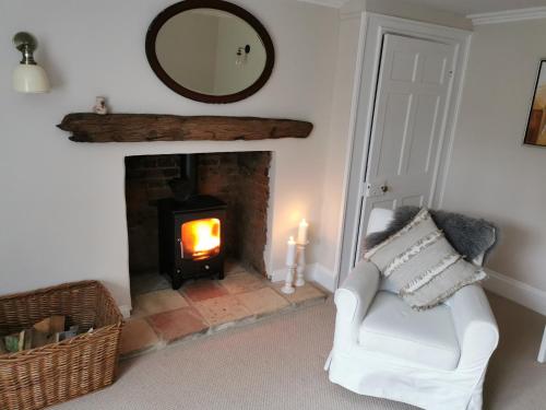 a living room with a fireplace with a chair and a mirror at Beehive Cottage in Beccles