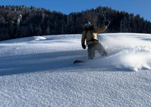 a man riding a snowboard down a snow covered slope at Khikhani Palace in Khulo
