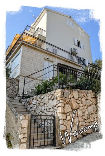 a house with a stone wall and stairs in front at Apartments T&M in Vinišće