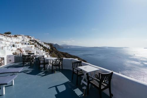 a row of tables and chairs on a balcony overlooking the ocean at Aspa Caves in Oia