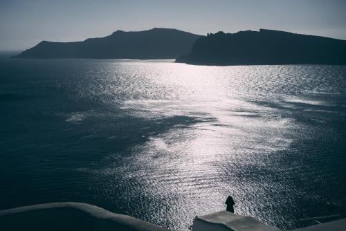 a person standing on the edge of a body of water at Aspa Caves in Oia