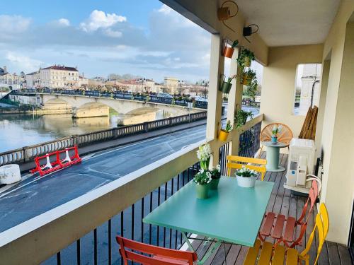 een tafel en stoelen op een balkon met uitzicht op een rivier bij "Au Fil de la Charente" - Coeur de Saintes - WIFI Clim - Classé 4 étoiles - 4 pers in Saintes