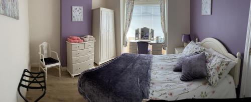 a bedroom with purple walls and a bed and a dresser at TJ’s Cottage in Enniskillen