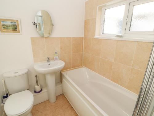 a bathroom with a toilet and a sink and a tub at The Dormie House in Silloth