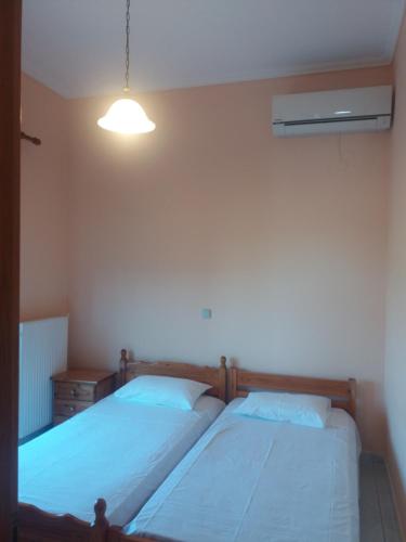 two twin beds in a bedroom with a light at Irini's appartment in Néa Koútali