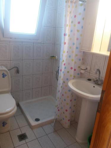 a bathroom with a shower curtain and a sink at Irini's appartment in Néa Koútali