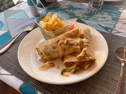 a white plate with food and french fries on a table at Nungwi Beach Front in Nungwi