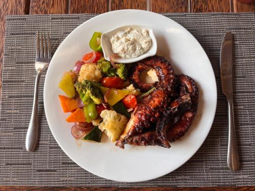 a plate of food with sausage and vegetables on a table at Nungwi Beach Front in Nungwi