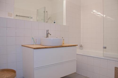 y baño blanco con lavabo y ducha. en Blue Lotus Apartment en Viena