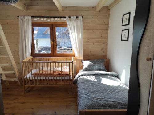 een slaapkamer met een wieg, een raam en een bed bij Agroturystyka w Maruszynie in Maruszyna