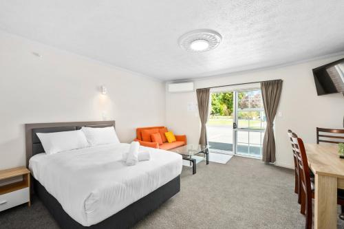 Habitación de hotel con cama, mesa y escritorio. en Ashleigh Court Motel, en Rotorua