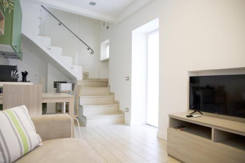 uma sala de estar com um sofá e uma televisão e escadas em La brezza del lago em Marone