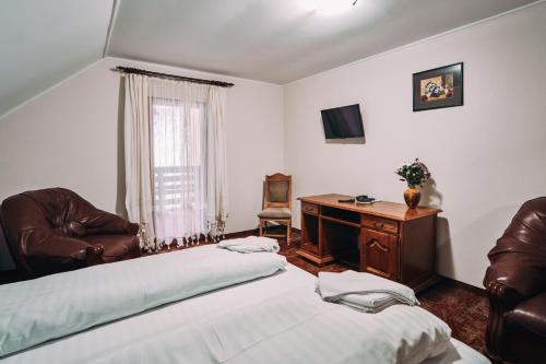 Schlafzimmer mit einem Bett, einem Schreibtisch und Stühlen in der Unterkunft Complex Turistic Bucovina in Suceviţa