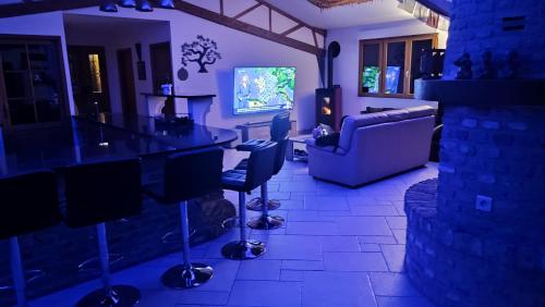 a living room with a bar with a couch and a tv at Les Gîtes KARMA in Andres