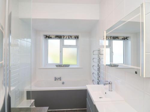 Baño blanco con bañera y lavamanos en Windy Heath en Salcombe
