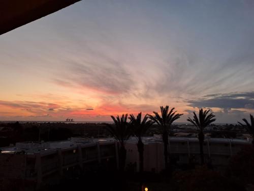 a sunset with palm trees in front of a building at lasuita- exclusive suites cesarea- sea view suite in Caesarea