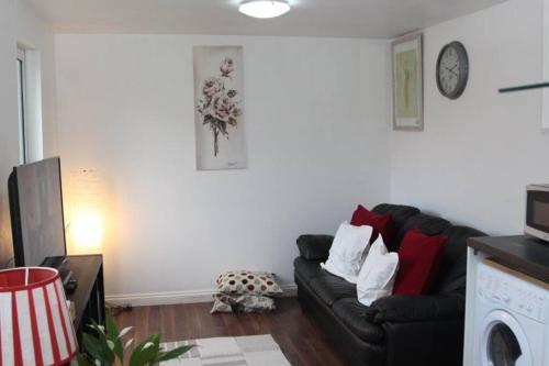 a living room with a black couch and a white wall at Cosy London holiday Home (Near O2 arena) in London